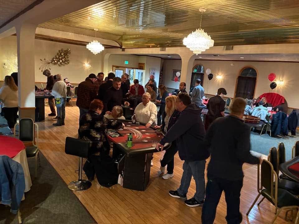 Guests gathered around gaming tables in a decorated hall at the club’s Casino Night fundraiser.