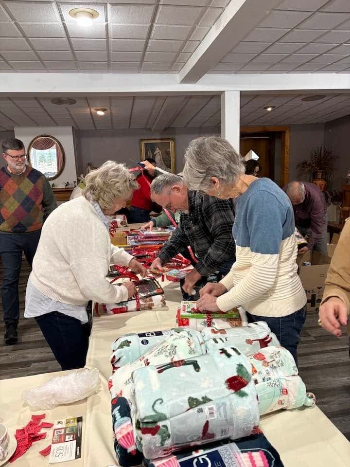 Club members sorting and wrapping donated blankets and holiday gifts around a long table.